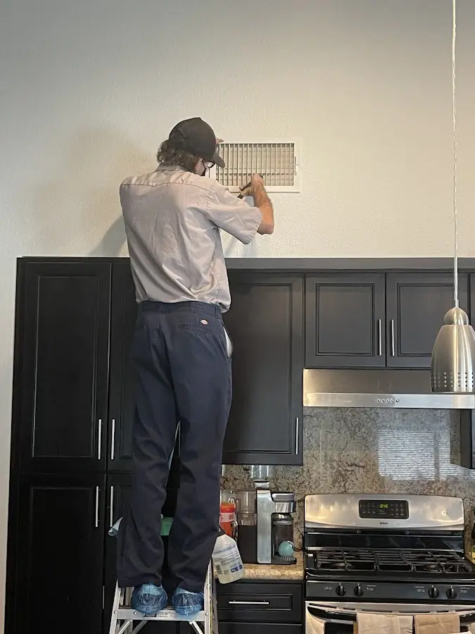 Technician inspecting an air vent during HVAC service in Lexington